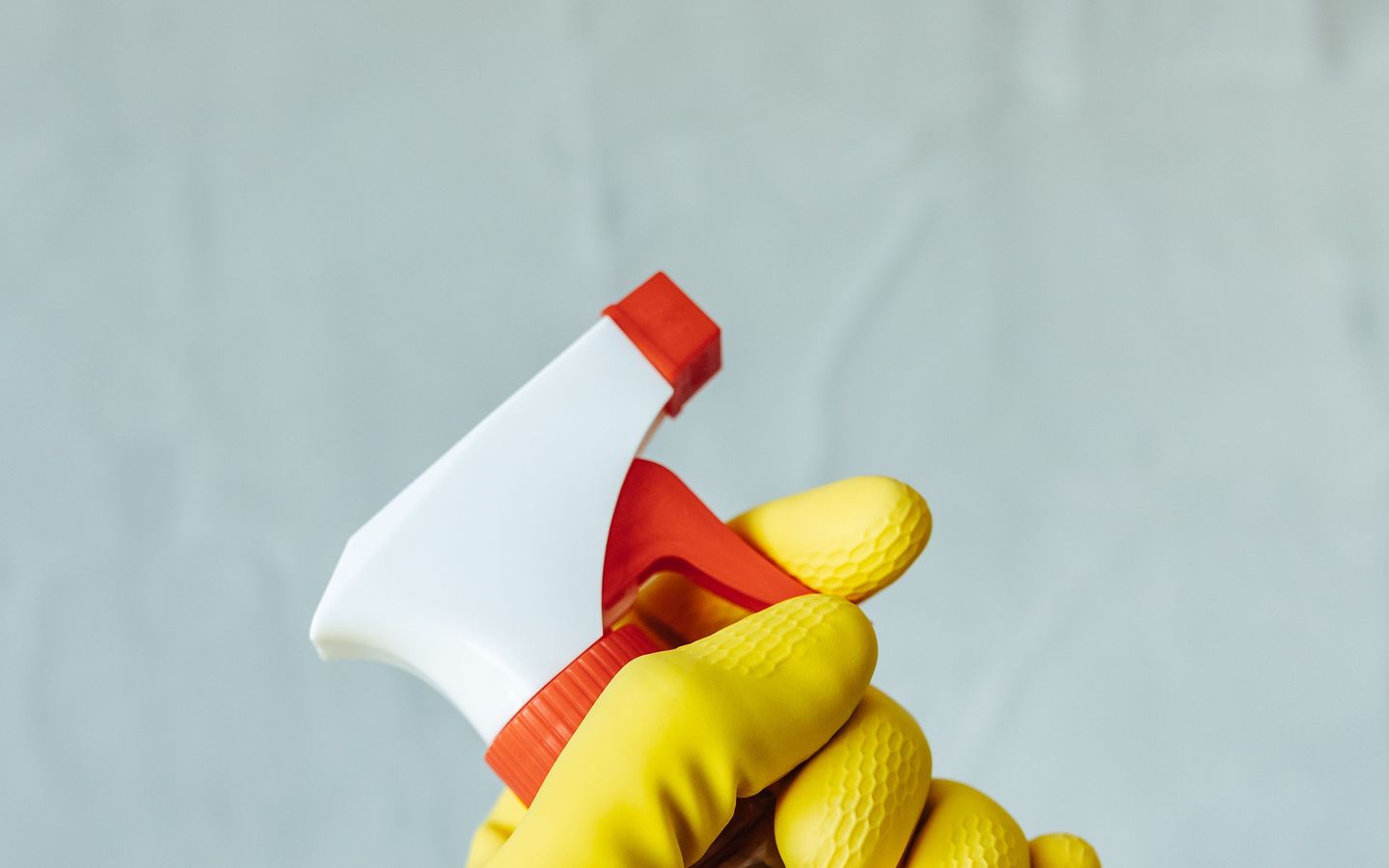 A gloved hand holding a trigger spray bottle.